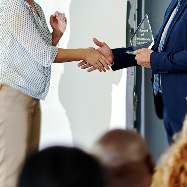 one individual holding an award while shaking hands with another individual